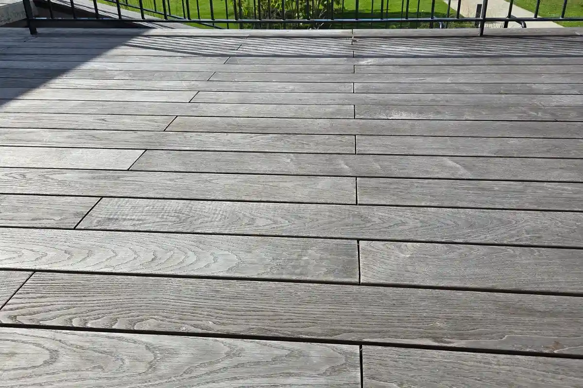 Weathered grey wooden decking boards with visible natural grain and gaps between the boards.